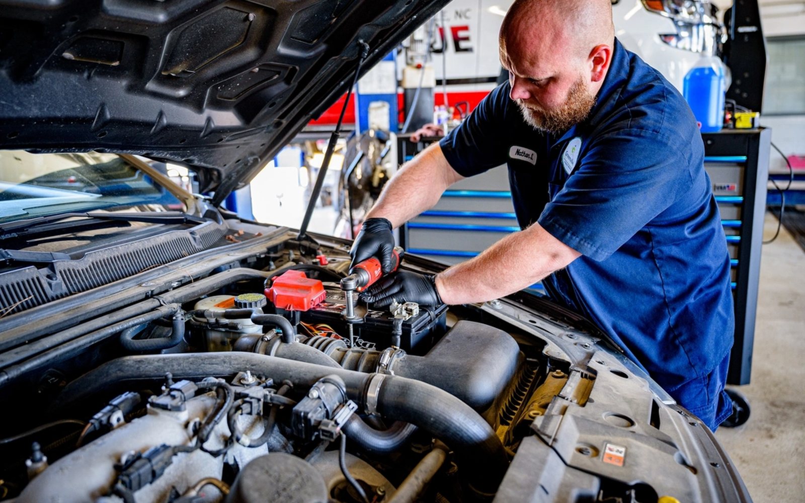 Mobile mechanic servicing a car in a driveway with a service van nearby